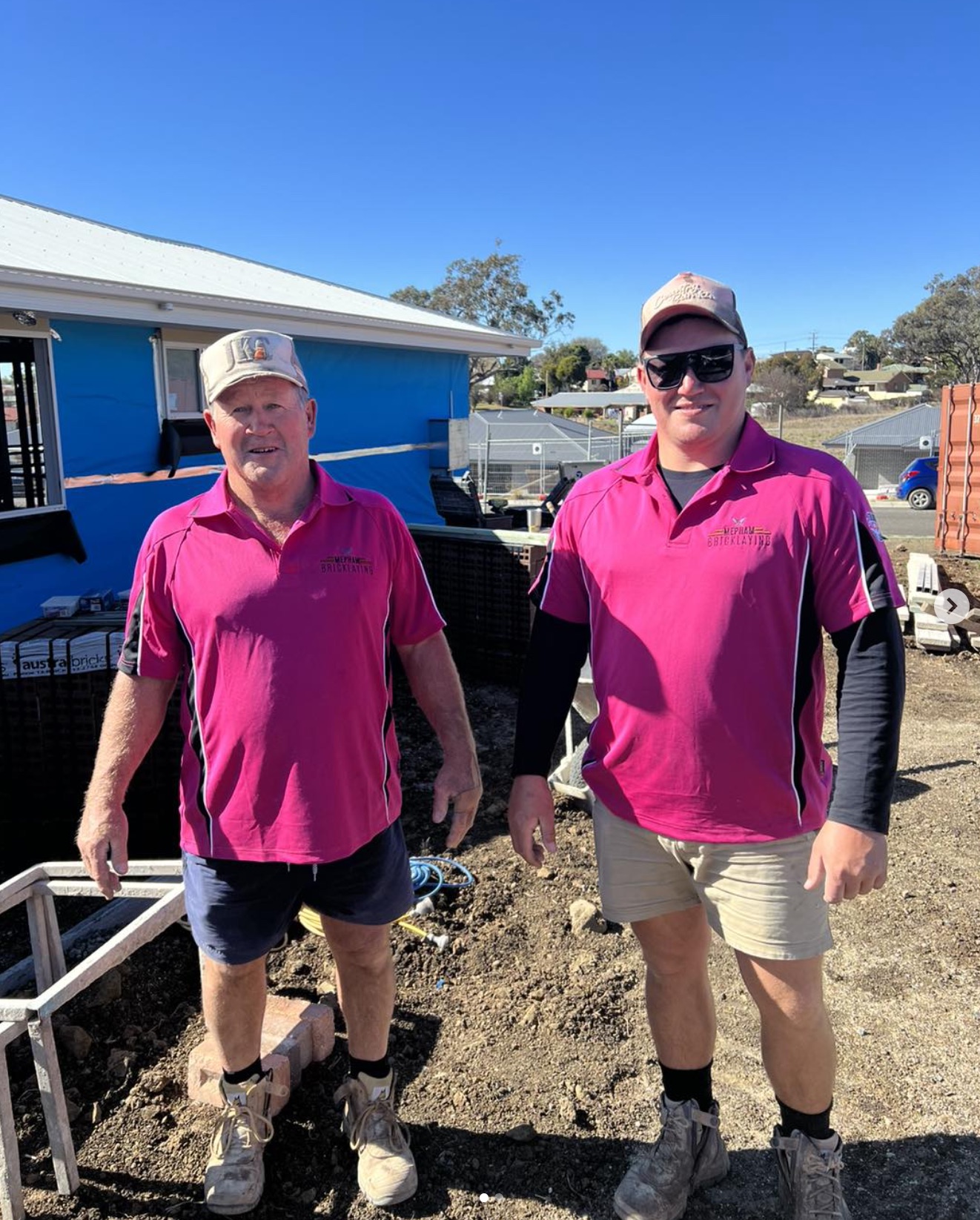 Two tradies wearing pink on a building site